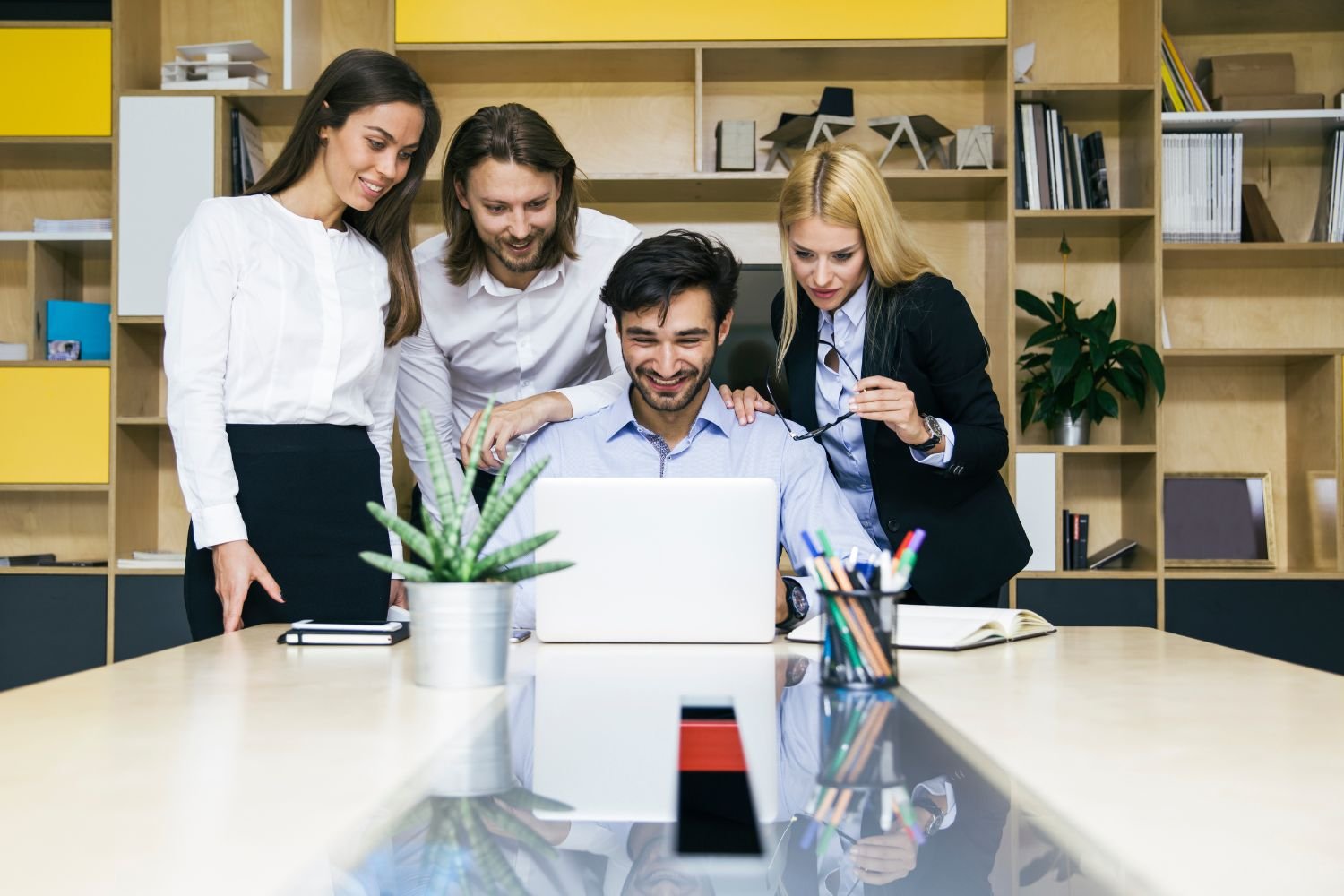 FavortechIT expert team collaborating around a laptop in a modern office, delivering innovative IT services, digital solutions, and proven business results.